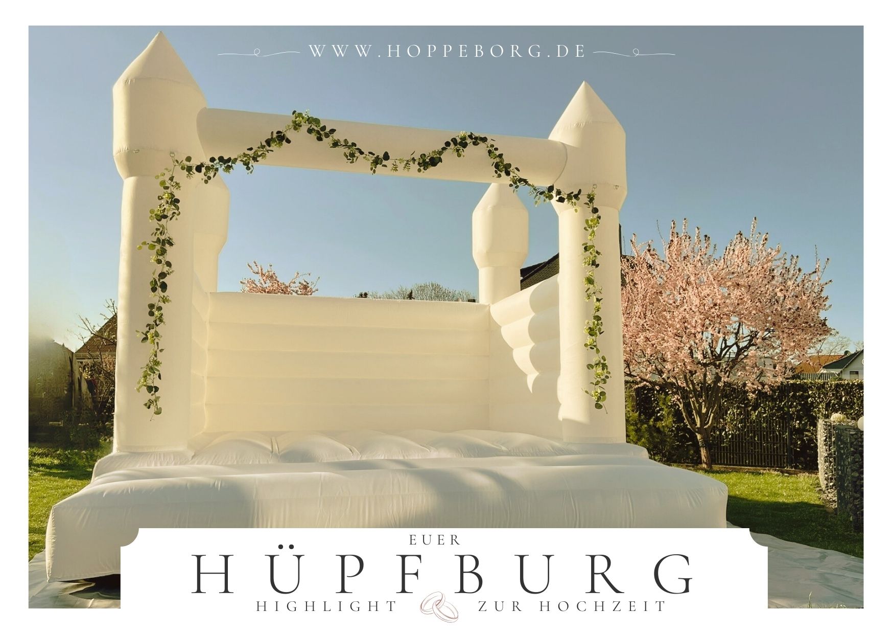 Weiße Hüpfburg mit Efeu-Dekoration als Highlight für Hochzeiten, präsentiert im Freien bei strahlendem Sonnenschein.